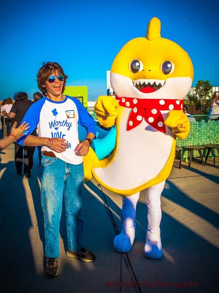 a teenager standing next to a yellow Baby Shark